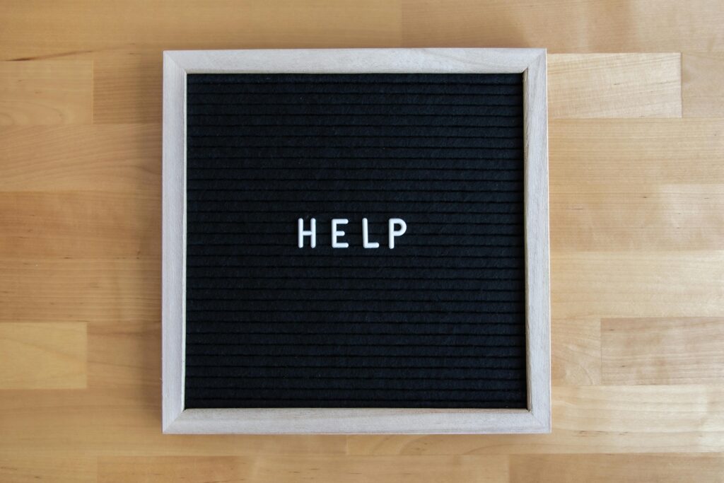 A letter board displaying the word HELP on a wooden surface, offering a minimalistic and modern look.